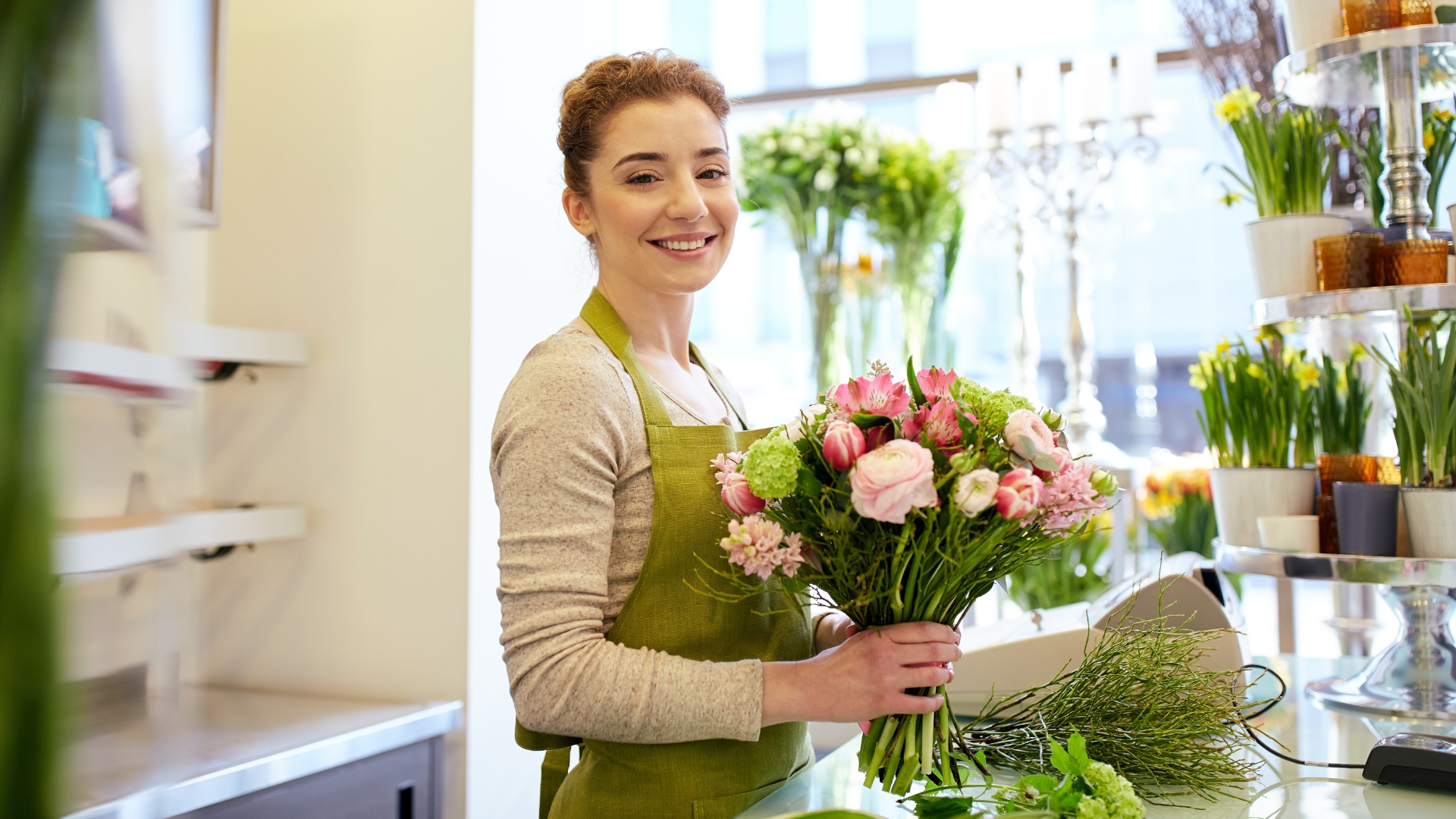 Fleuriste souriante préparant un bouquet dans sa boutique pour attirer des clients locaux